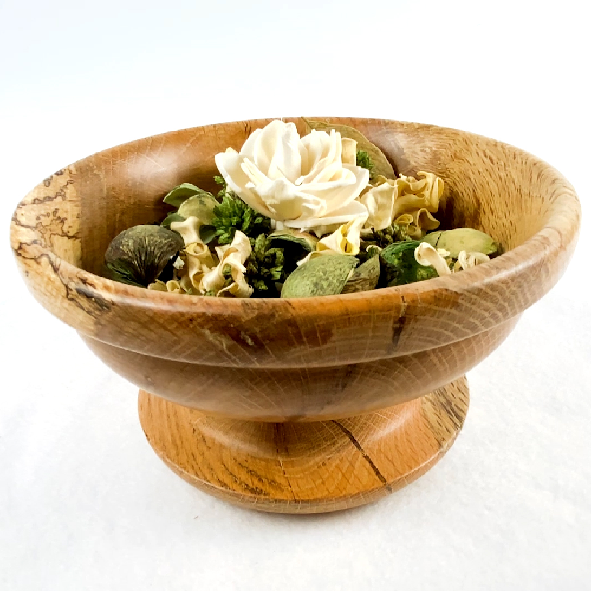 A wooden bowl filled with dried flowers and potpourri on a white background A wooden bowl filled with dried flowers and potpourri on a white background
